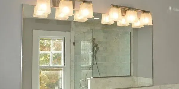 Bright bathroom with glass shower enclosure and vanity lights above mirror