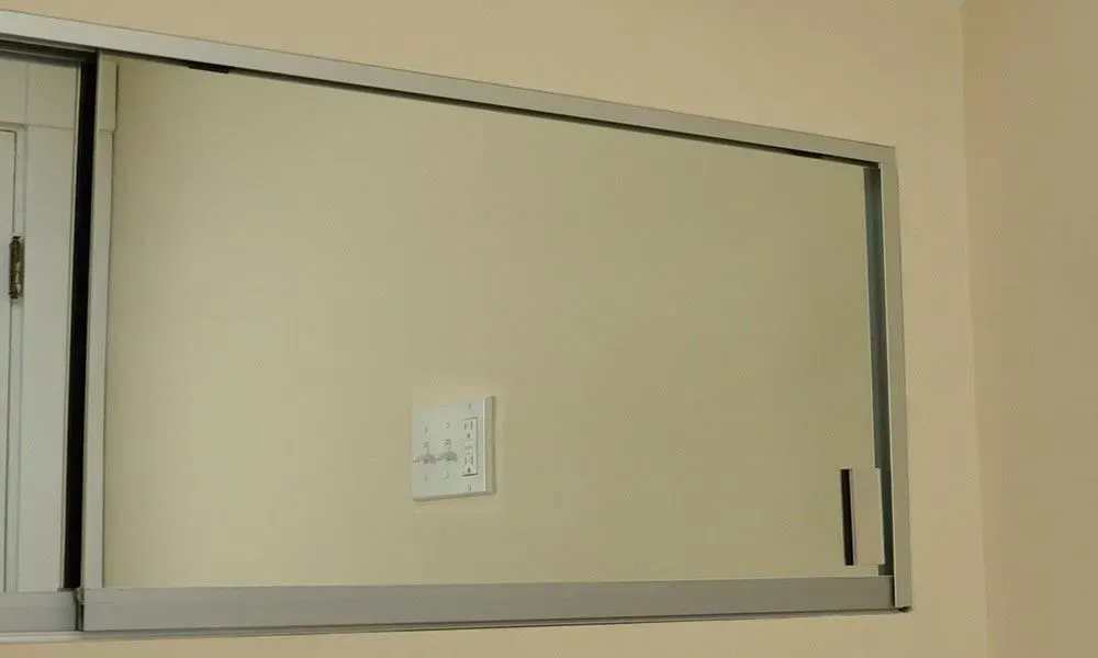 Wall-mounted rectangular cabinet with a white panel on a beige wall.