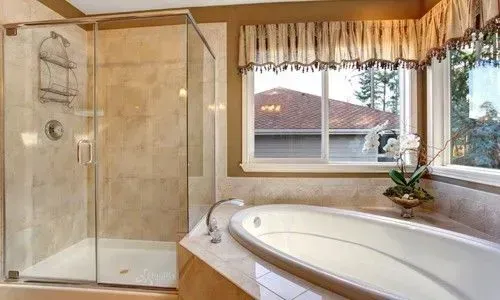 Elegant bathroom with glass shower, corner soaking tub, and large window with wood trim