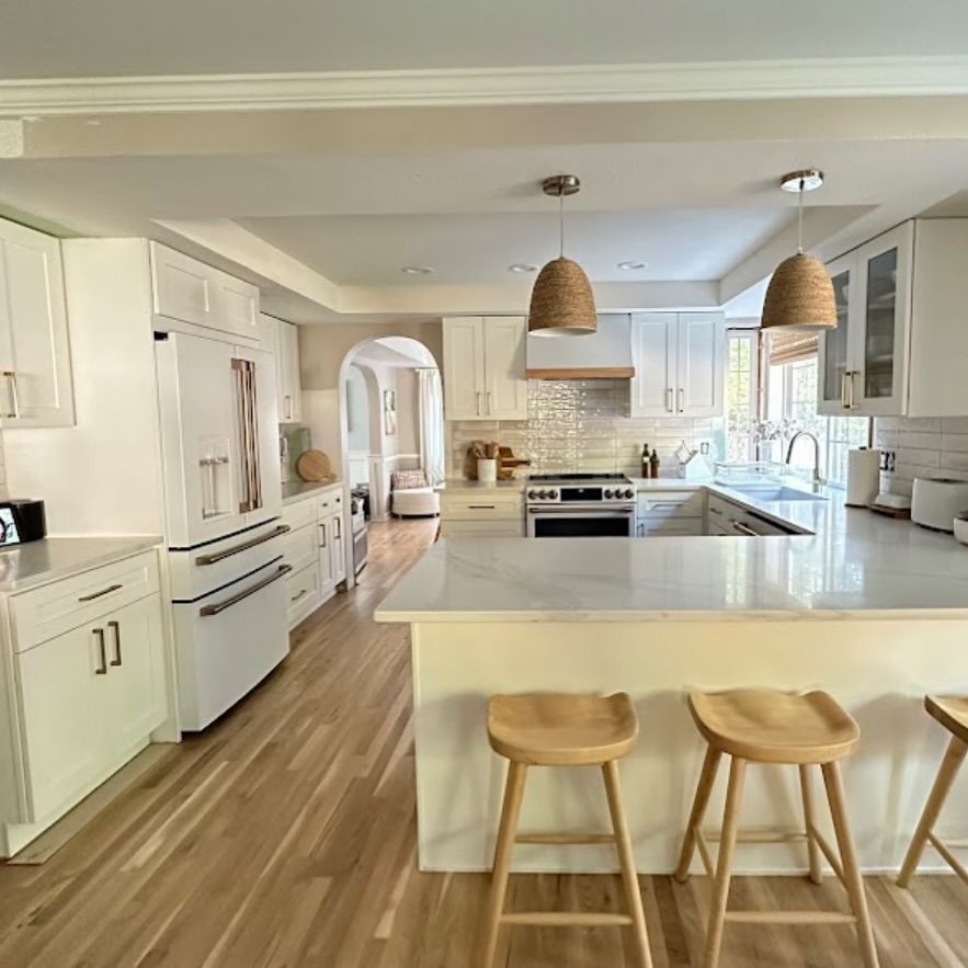 Bright, modern kitchen with white cabinets, light wood floors, and woven pendant lights.