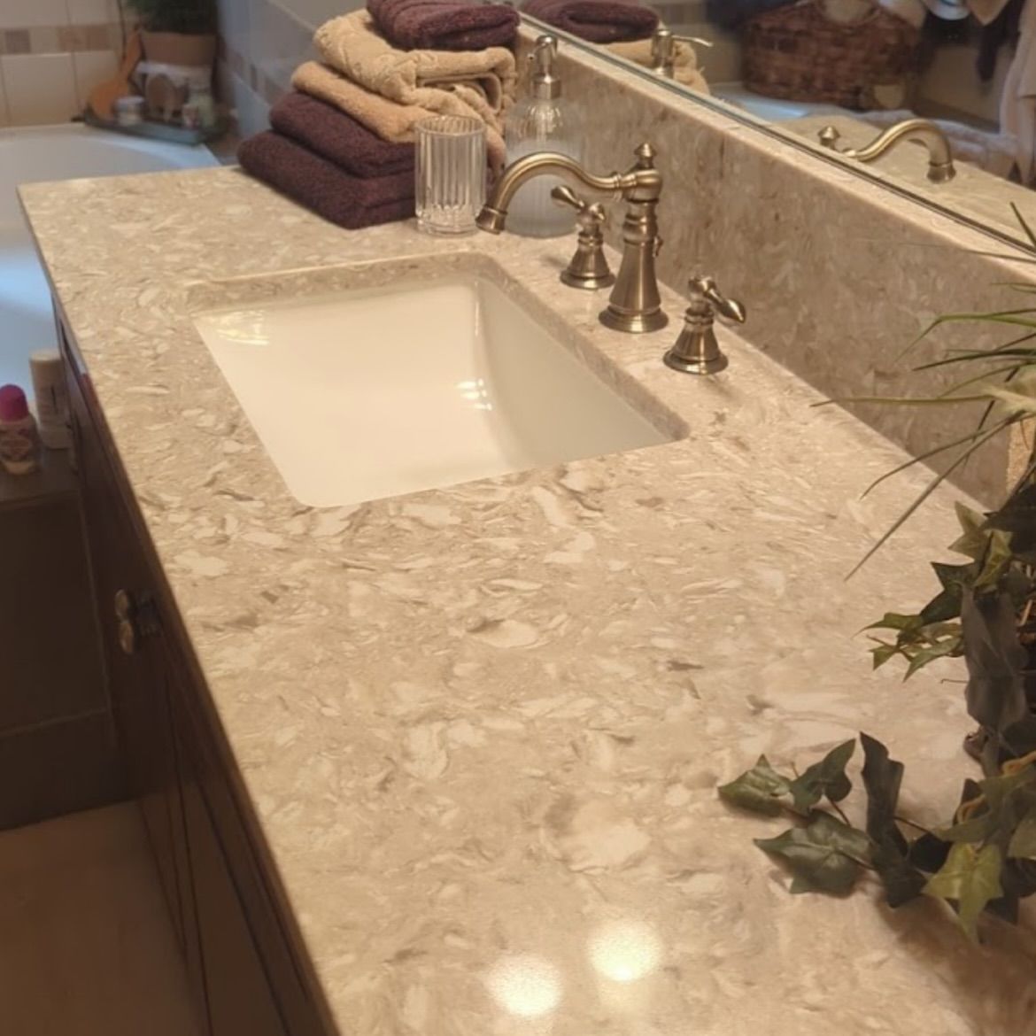 Bathroom vanity with a tan countertop, white sink, and bronze faucet.