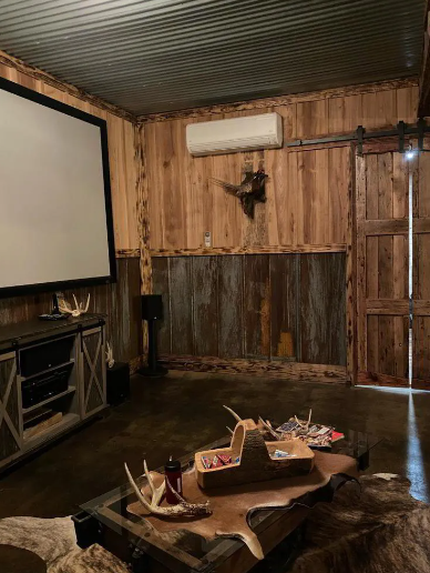 Cozy rustic room with a projector screen, wooden walls, and low table with trays on a cowhide rug