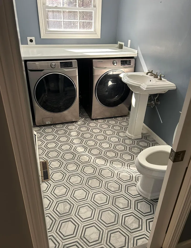 Laundry room with washer, dryer, pedestal sink, and patterned tile floor.