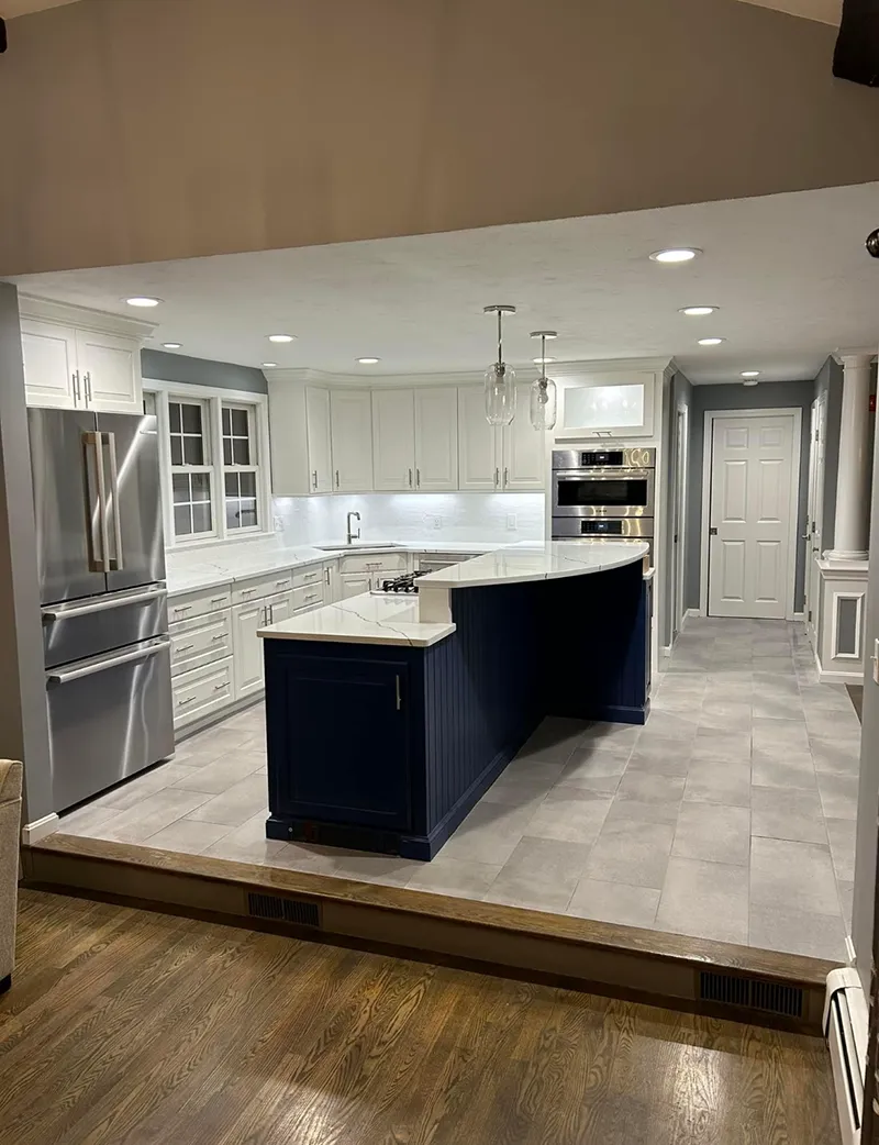 Newly renovated kitchen with blue island, white cabinets, and gray tile flooring.