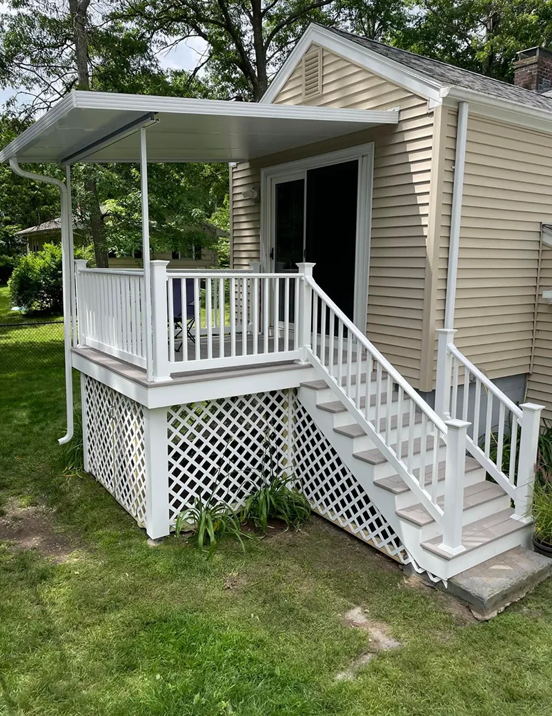 White deck with a covered patio, stairs, and lattice skirting, attached to a light yellow building.