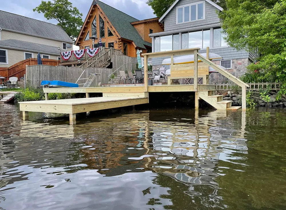 Wooden dock extending over water near houses; cloudy day.