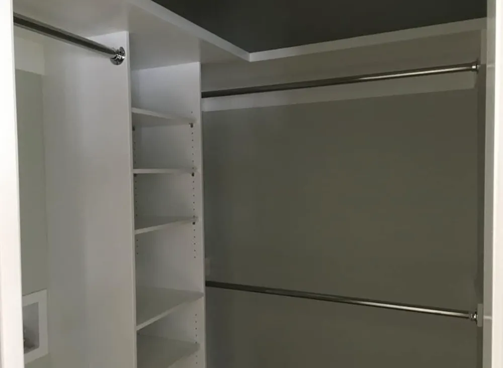 Empty white closet with shelves and rods.