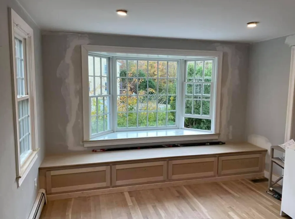 Interior view: Bay window with built-in bench. Light wood floors, white trim, and gray walls.