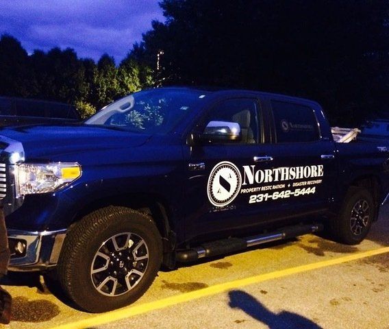 Dark blue Northshore truck with logo, parked. Phone number on side.