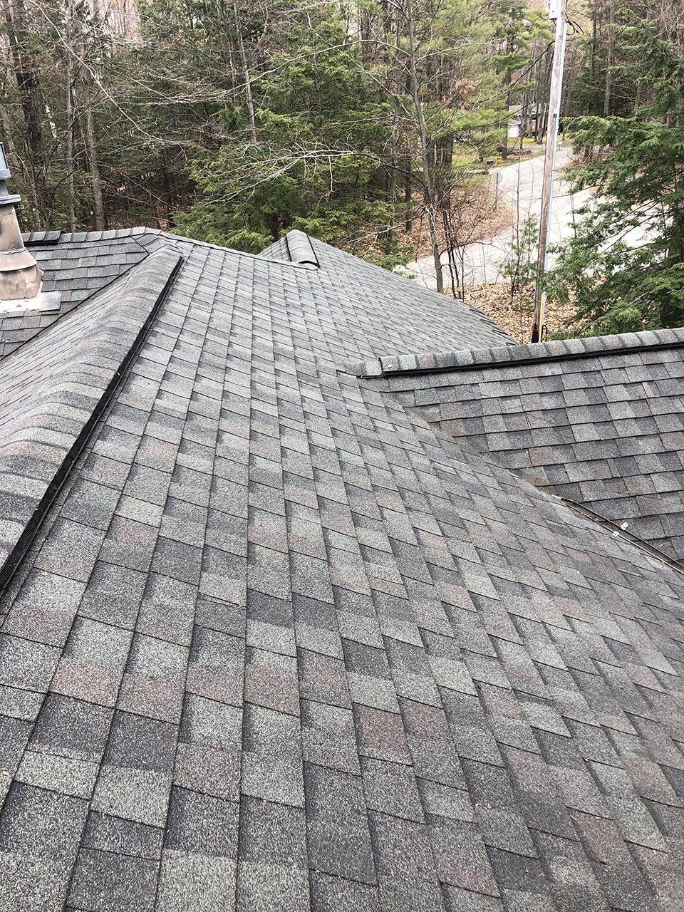 Asphalt shingle roof with varying shades of gray, extending to the horizon. Overlapping layers.