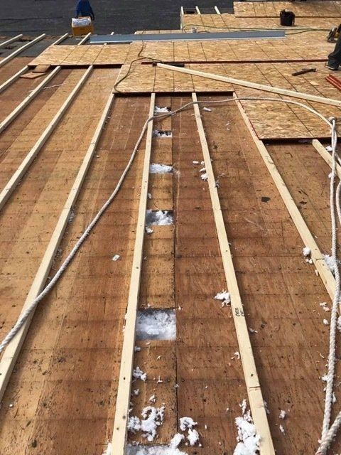 Roof under construction; wooden beams and panels visible, some insulation present.