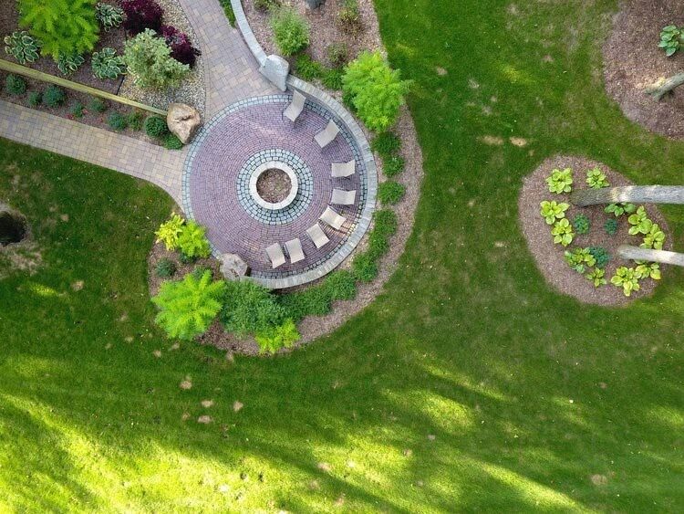 An aerial view of a lush green lawn with a fire pit in the middle.