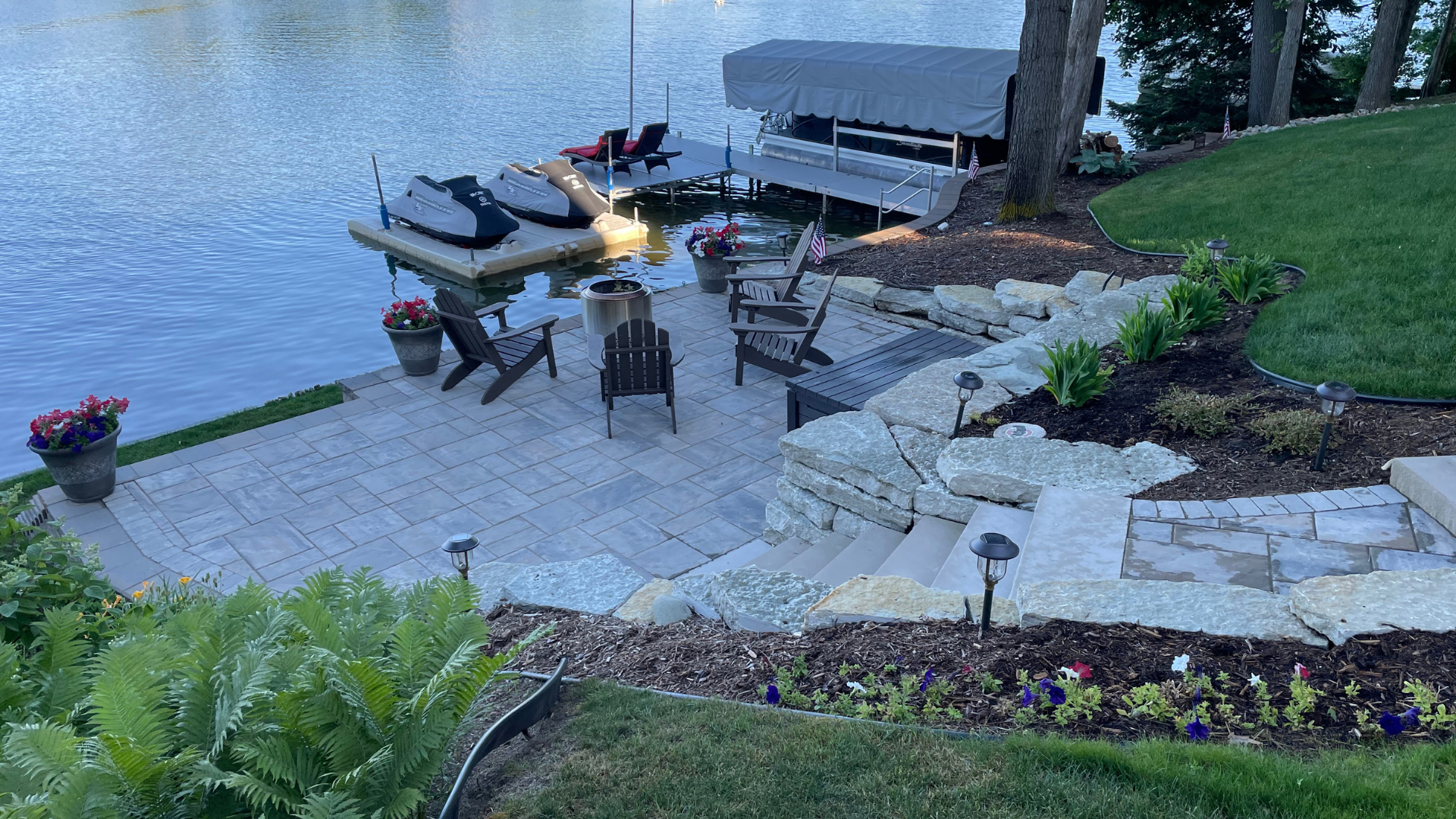 a patio with chairs and a dock next to a lake