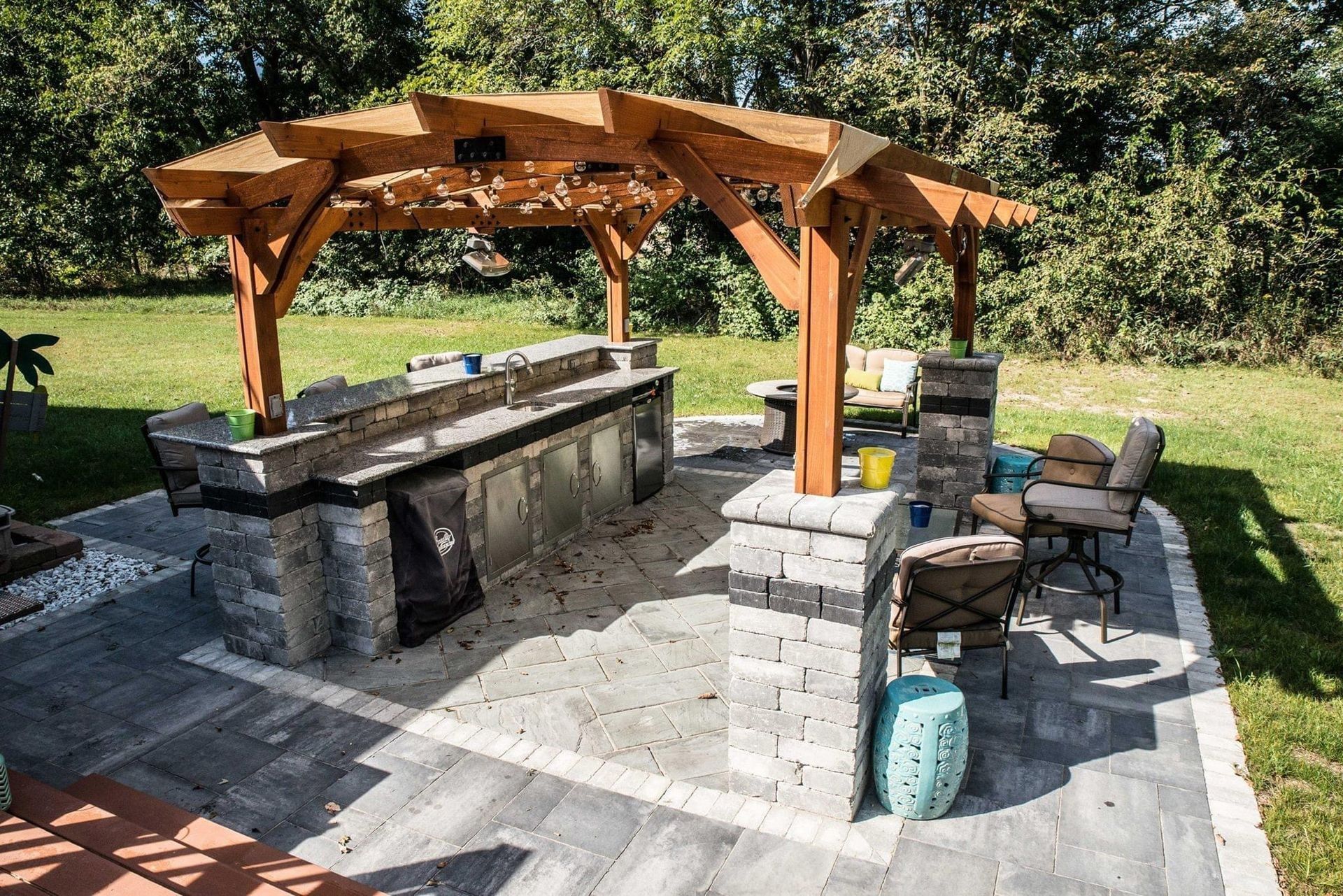 a patio with a wooden pergola and a kitchen in the backyard