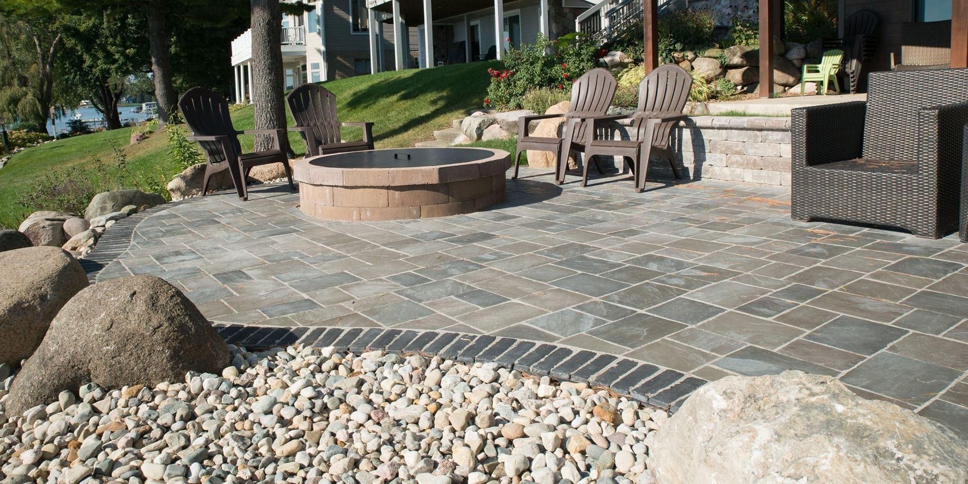 a patio with a fire pit and chairs in front of a house