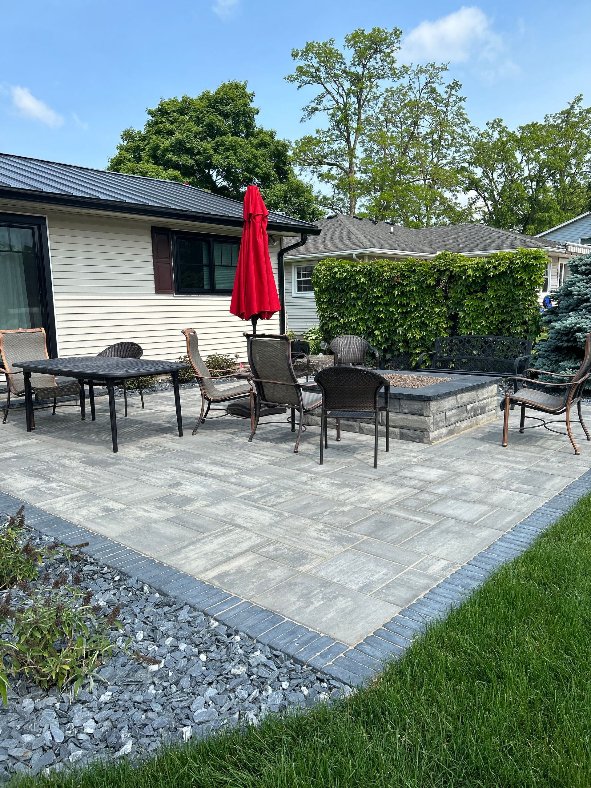 a patio with tables and chairs and an umbrella in front of a house