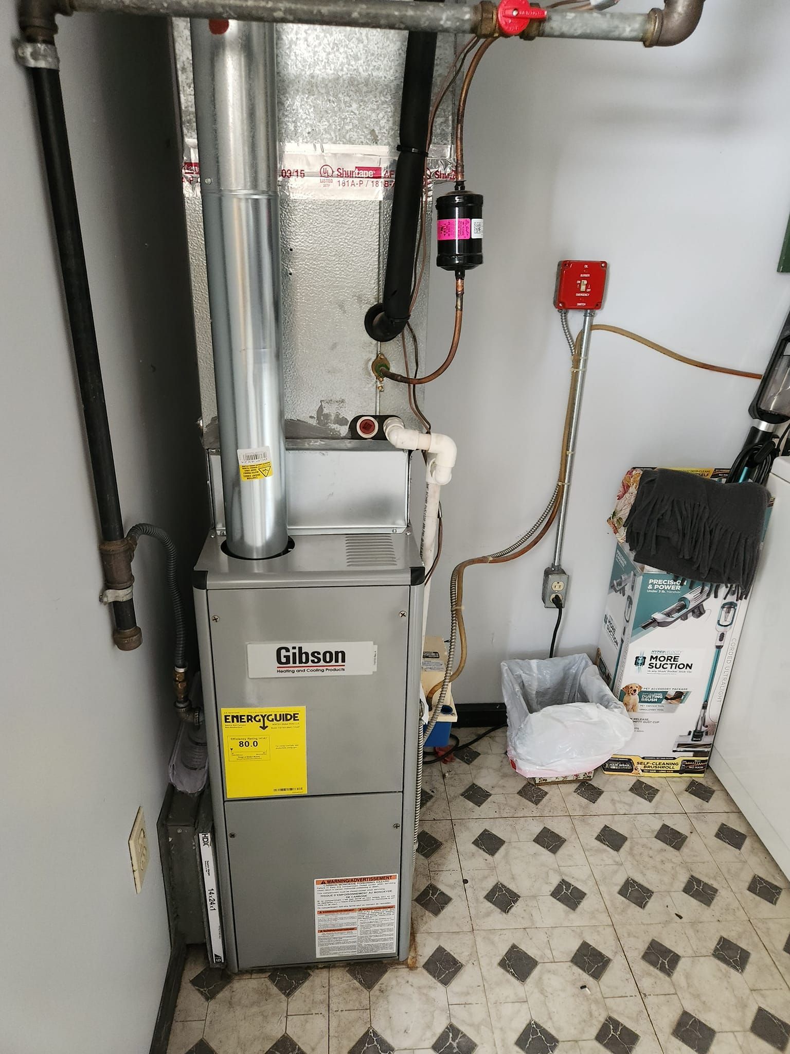 A gas furnace is sitting in a room next to a tiled floor.