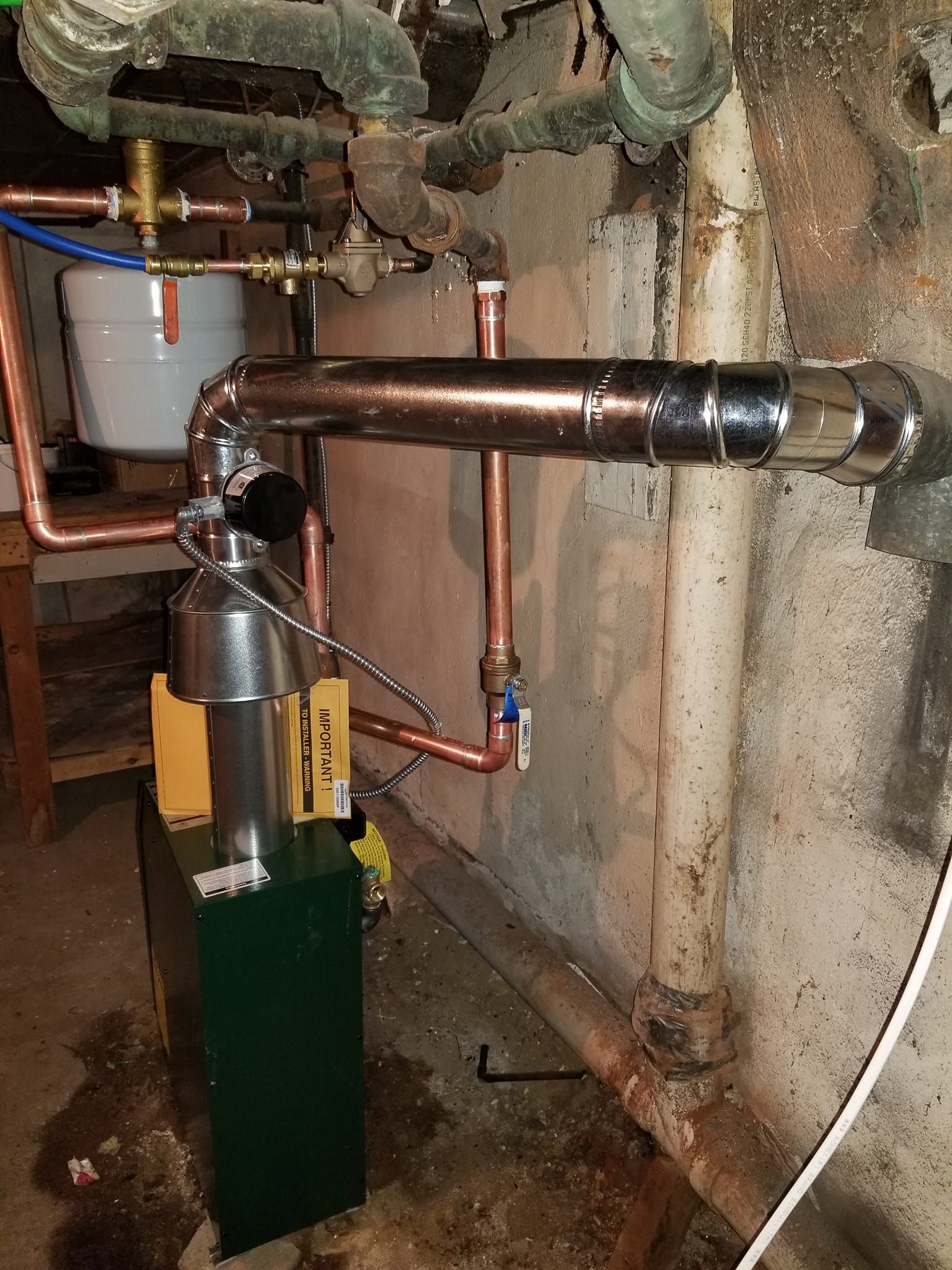 A copper pipe is connected to a boiler in a basement.