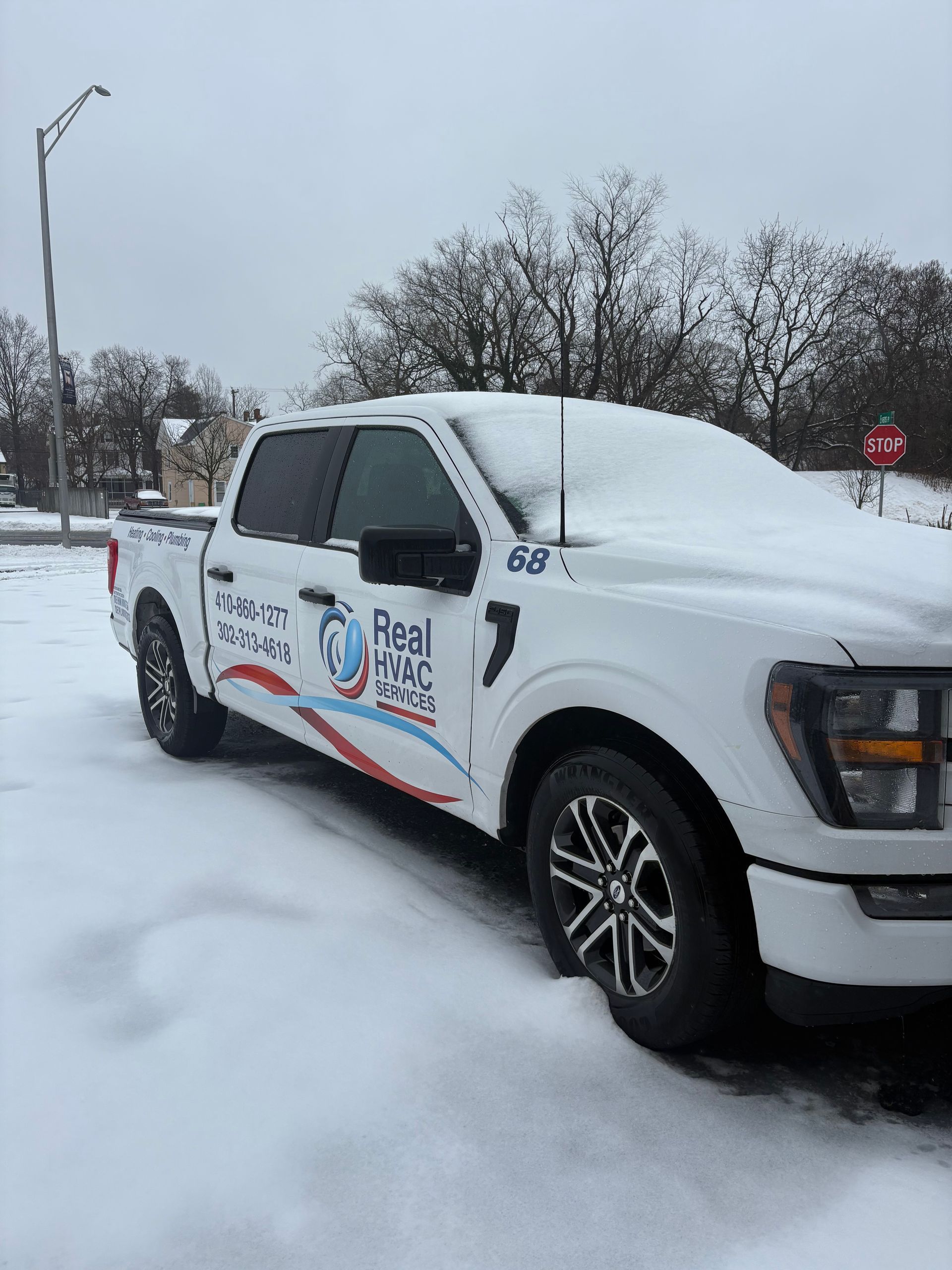 White pickup truck with company decals parked in deep snow on a snowy street