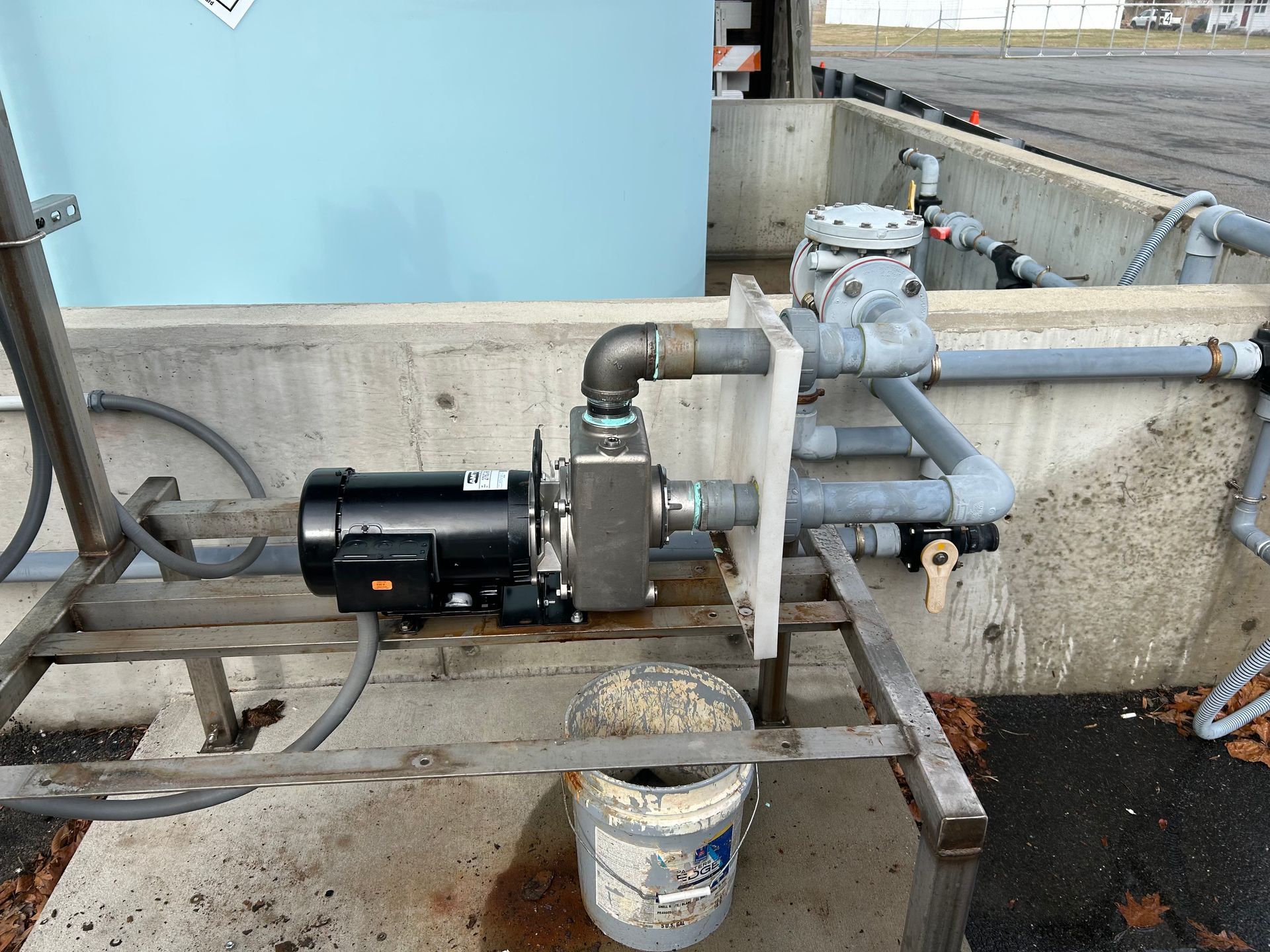 Industrial pump and valve assembly with pipes mounted on a concrete wall outdoors