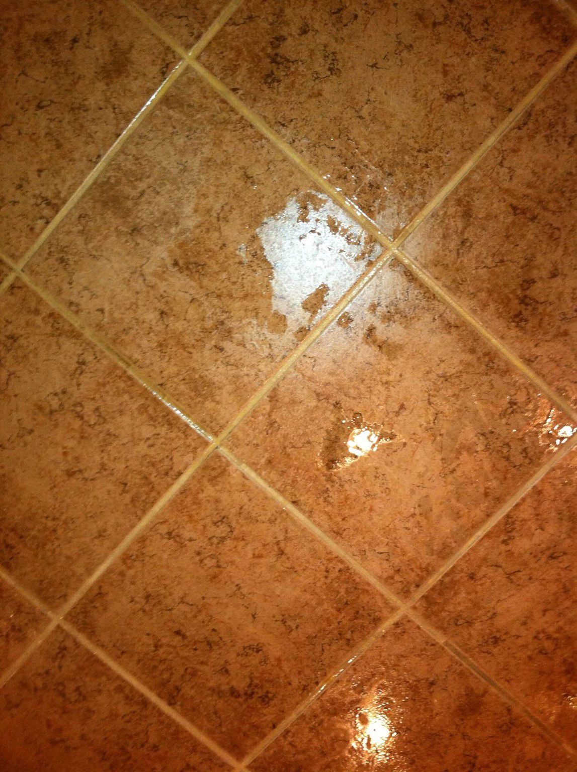 A close up of a tiled floor with a reflection of a light.