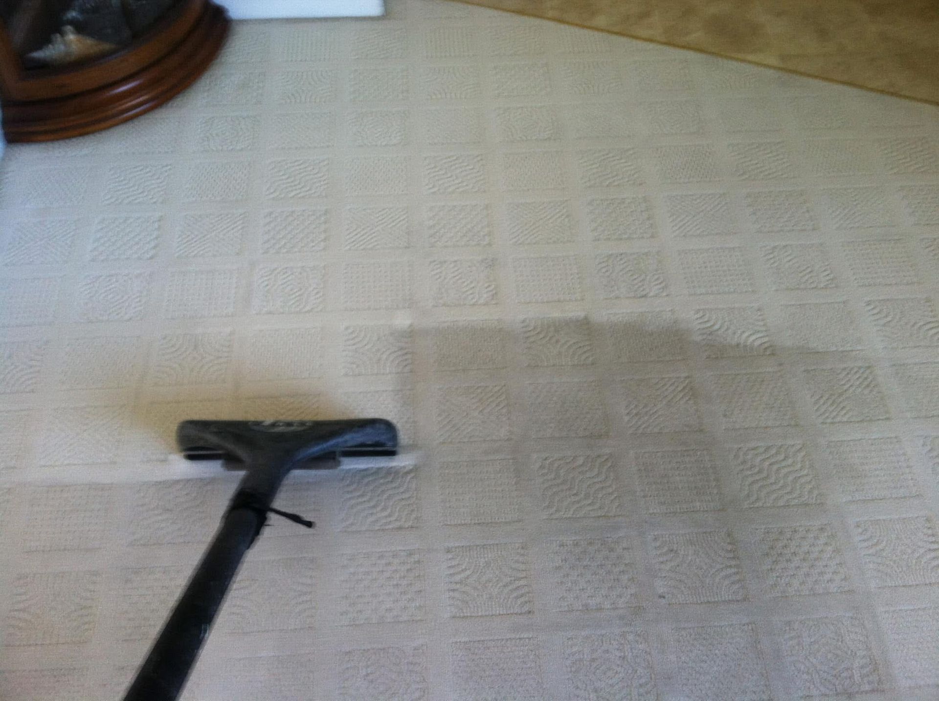 A vacuum cleaner is being used to clean a white carpet.