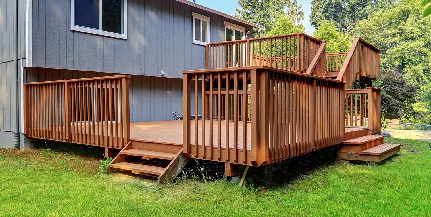 A large wooden deck is in the backyard of a house.