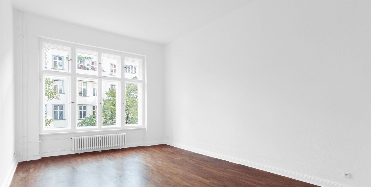 An empty room with hardwood floors and a large window.