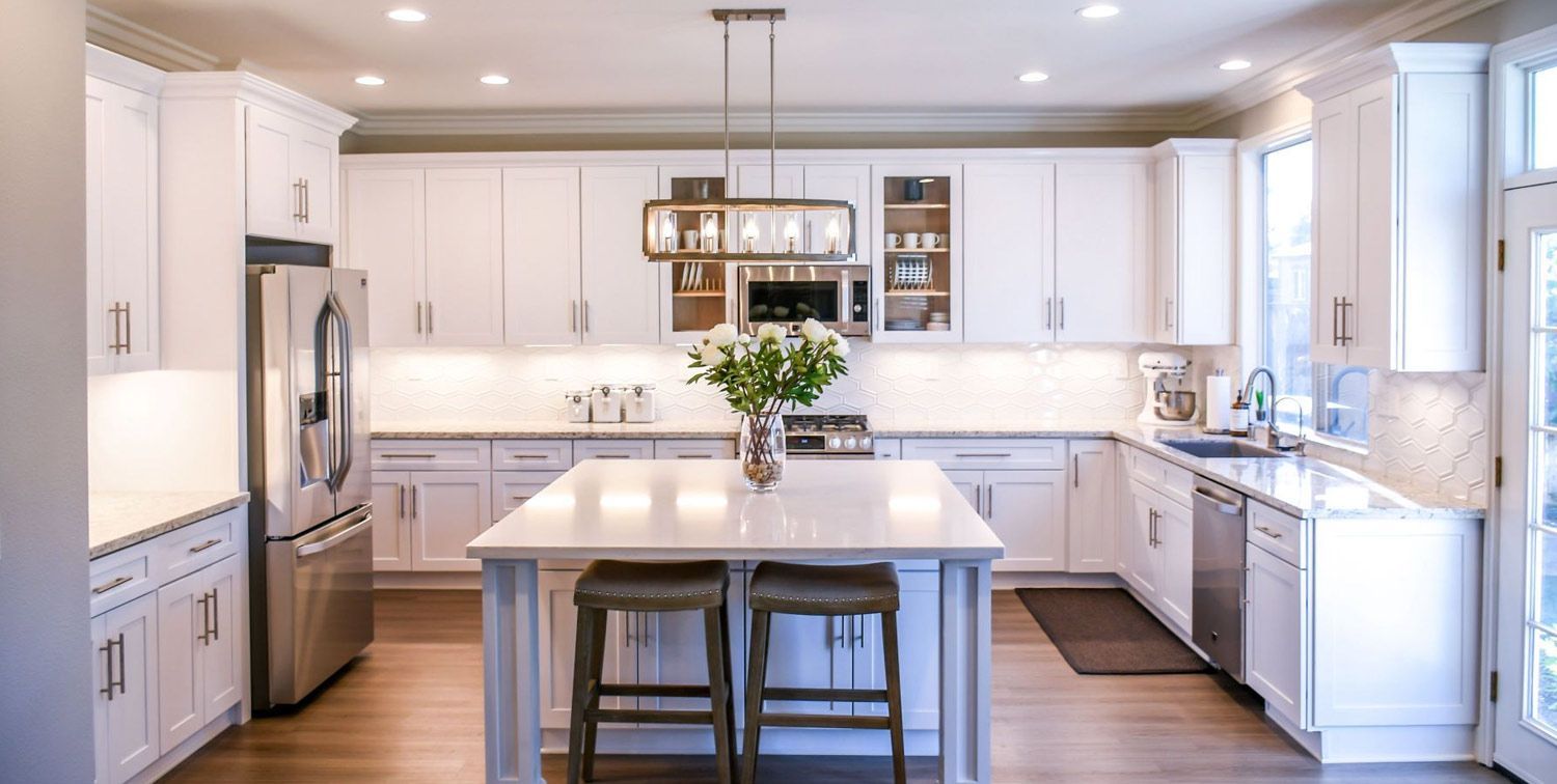 A kitchen with white cabinets, stainless steel appliances, and a large island.