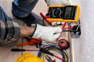 Electrician at work with the tester measures the voltage in an electrical system.
