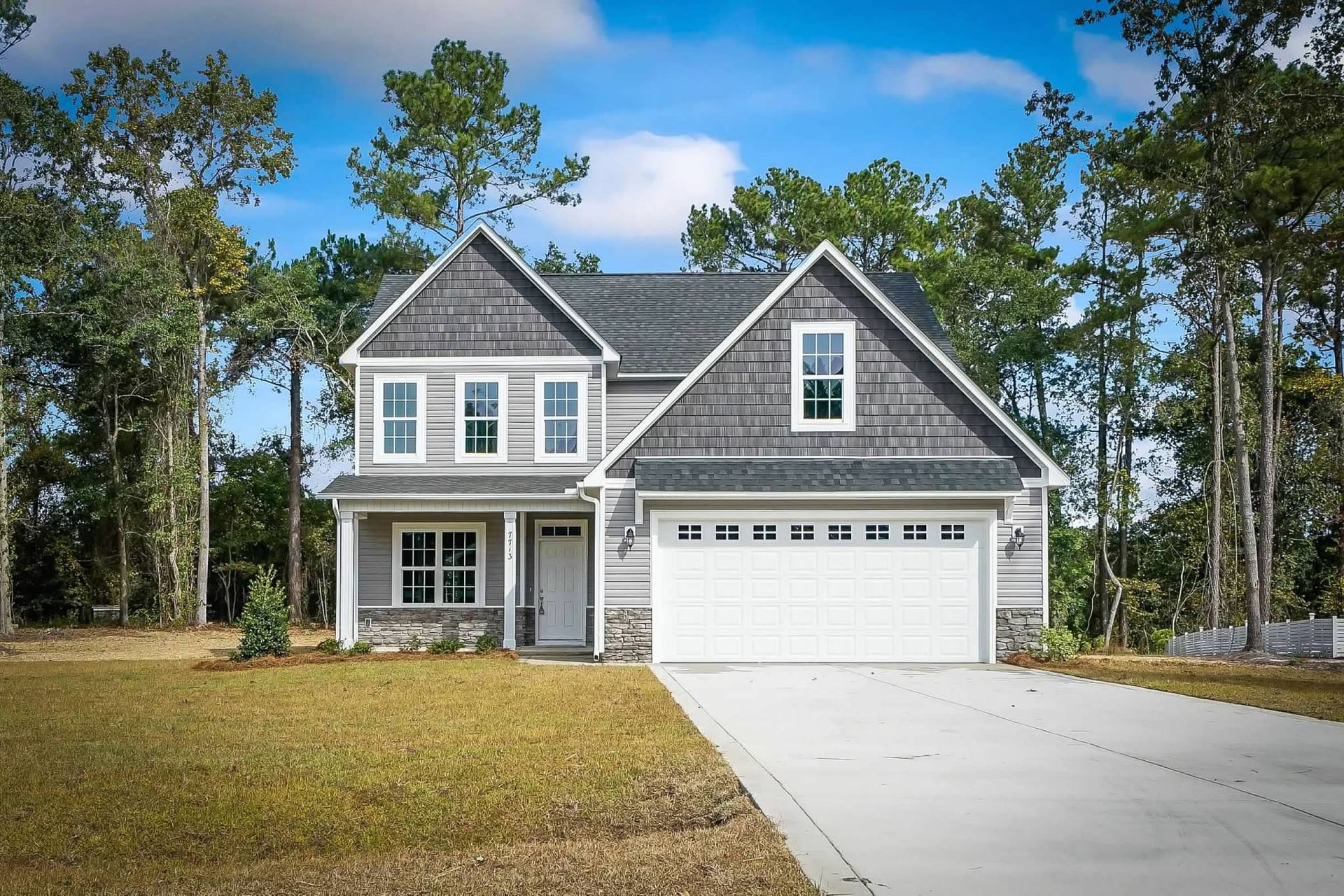 A large house with a white garage door is surrounded by trees