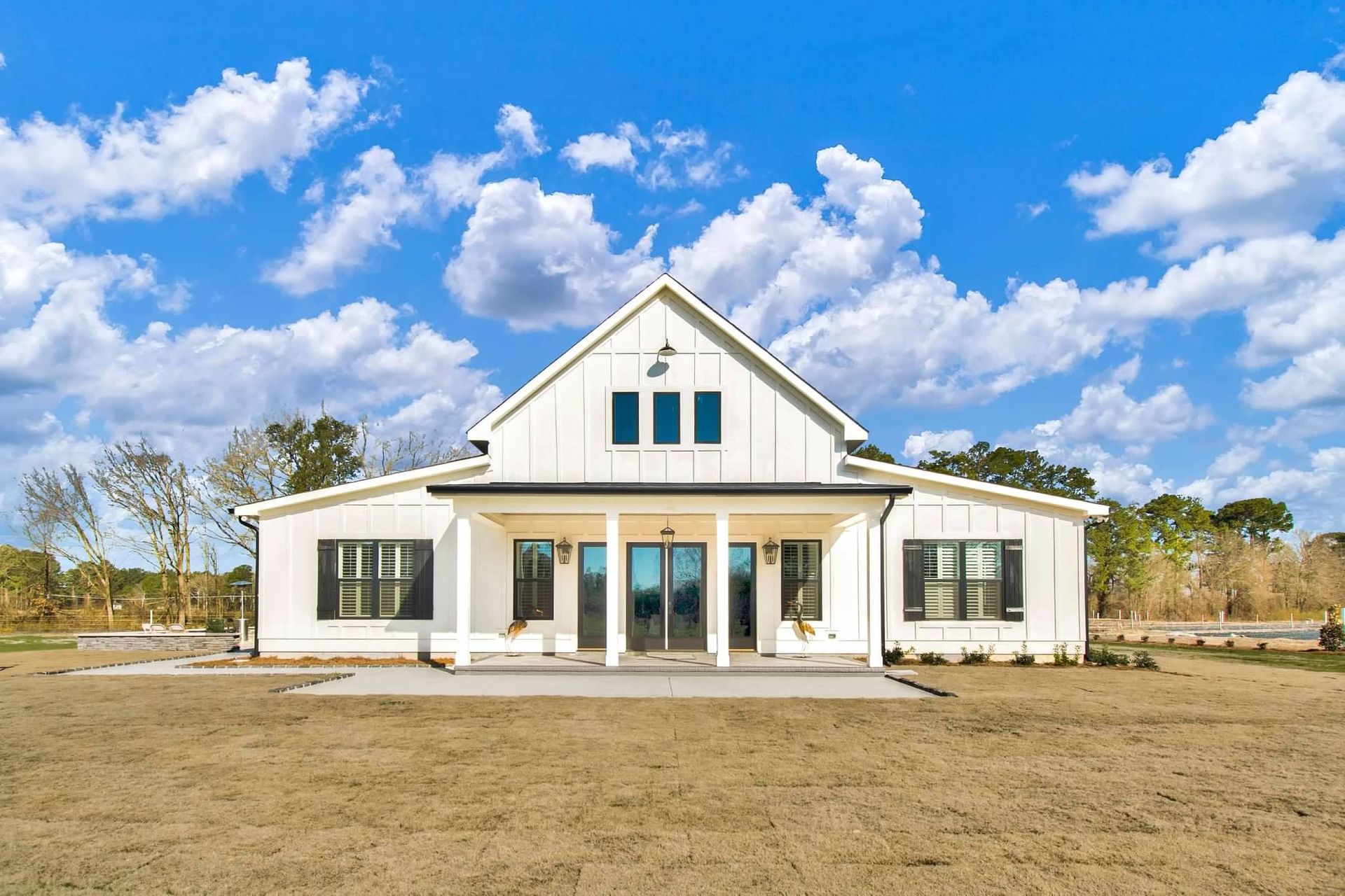 A large white house is sitting on top of a dirt field