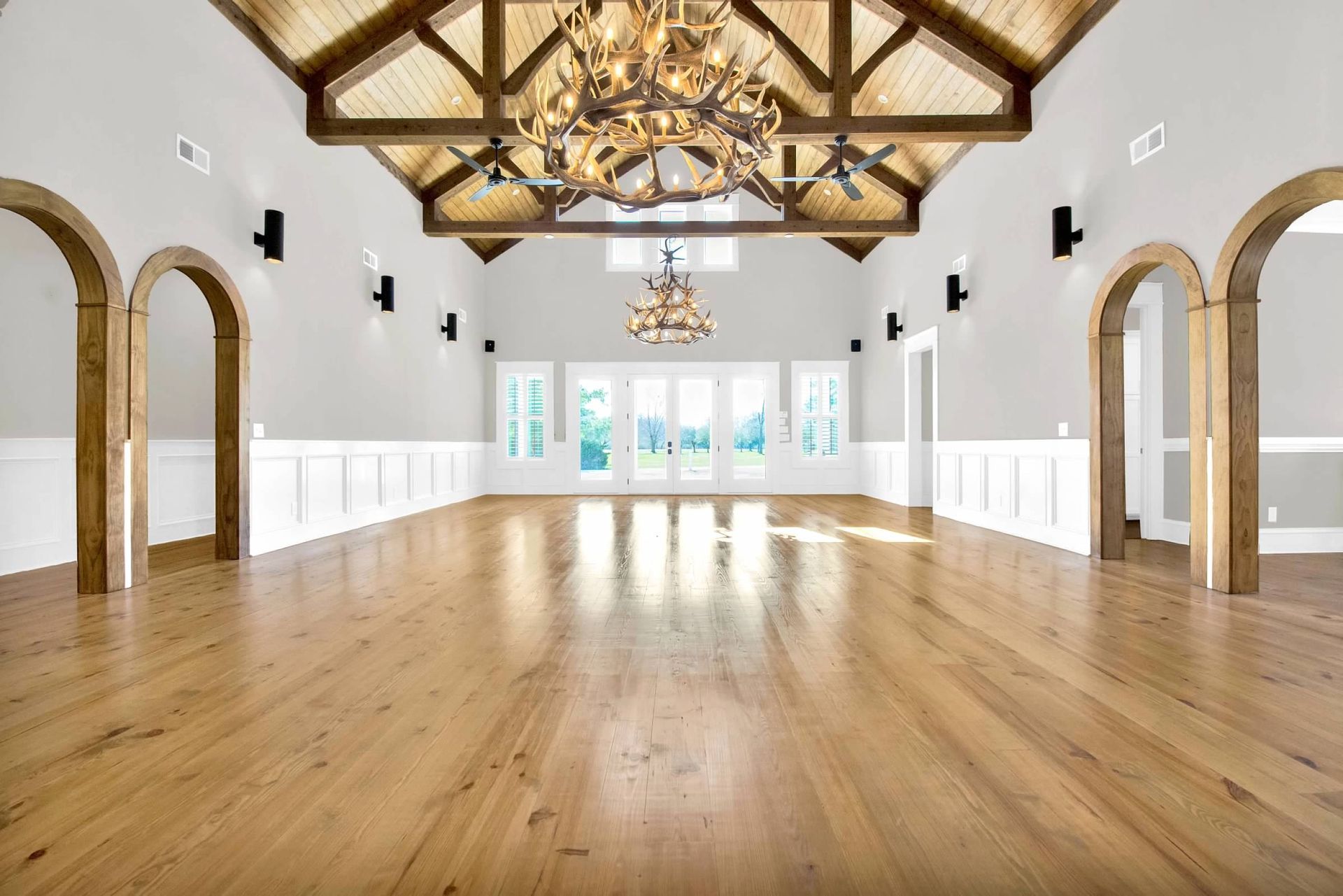 A large empty room with hardwood floors and a chandelier