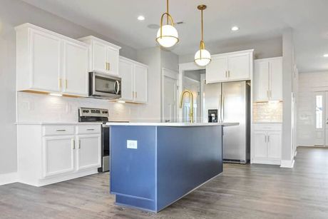 A kitchen with white cabinets , stainless steel appliances , and a blue island.