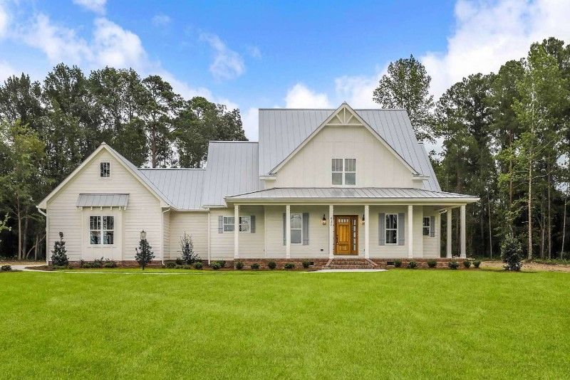 A white house with a metal roof and a porch