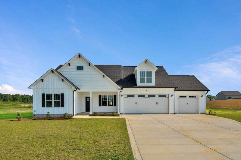 A large white house with a black roof and a large driveway.