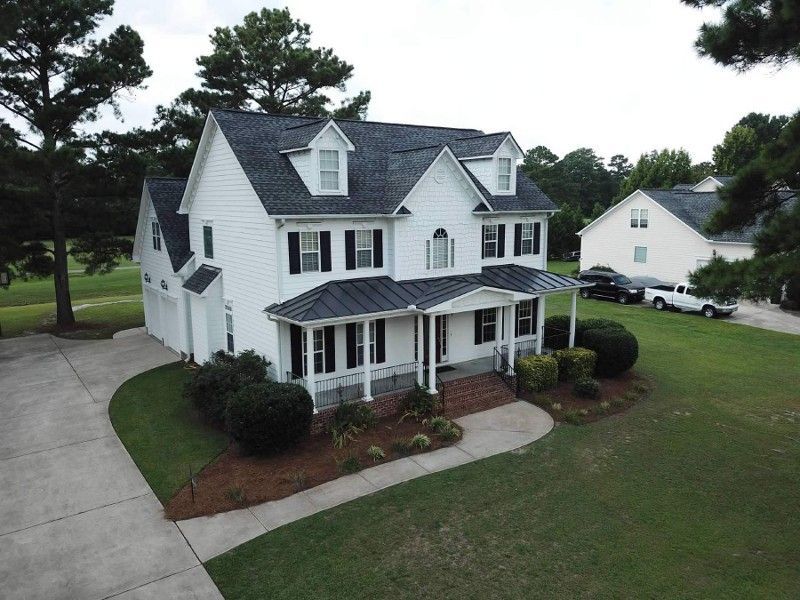 An aerial view of a large white house with a black roof