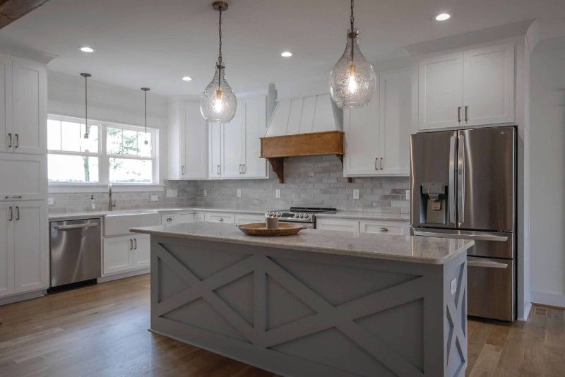 A kitchen with white cabinets , stainless steel appliances , and a large island.