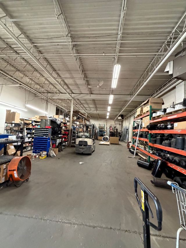 A wide warehouse aisle with shelves of tools and equipment under fluorescent lights.