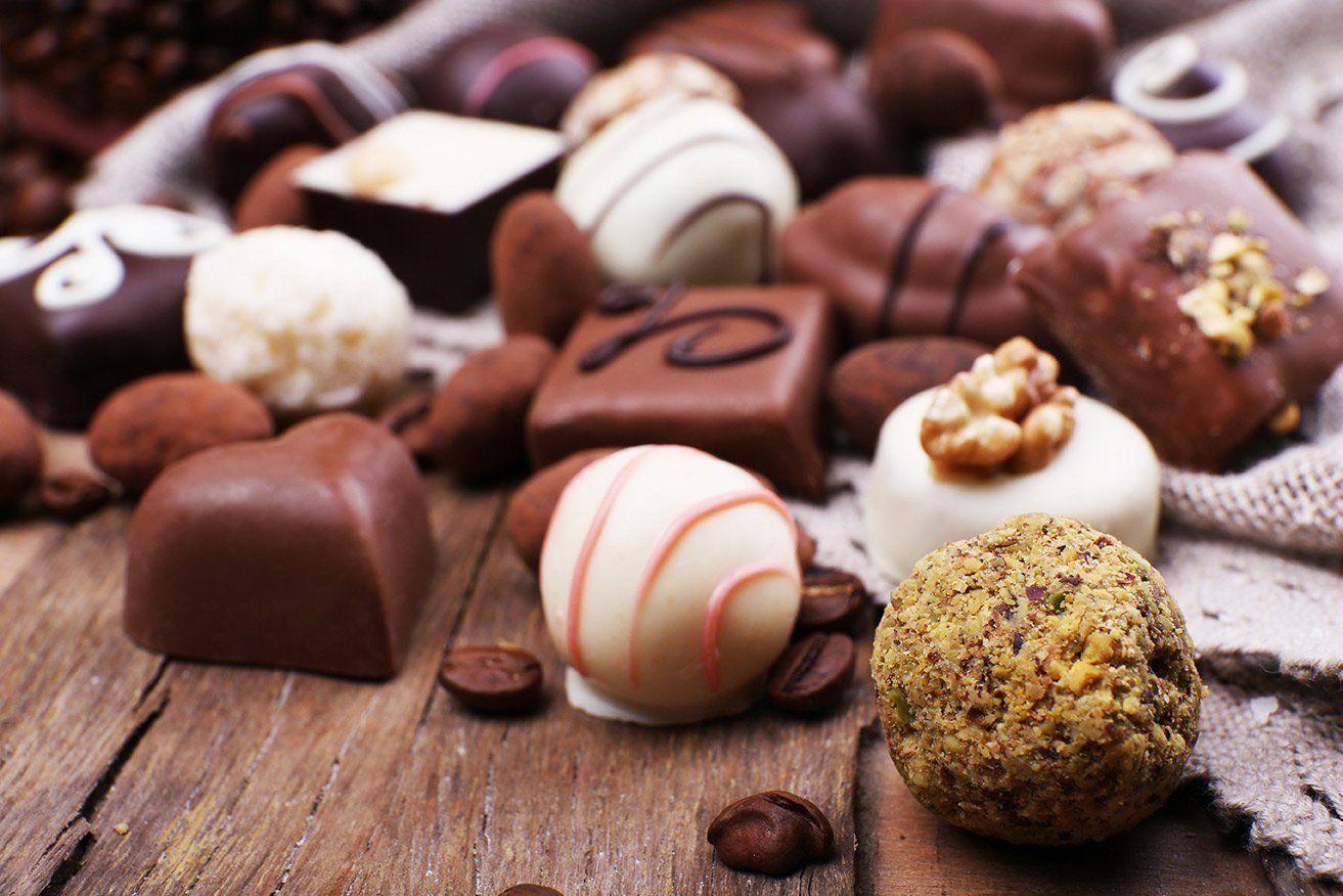 A wooden table topped with a variety of chocolates and nuts