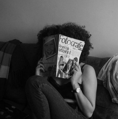 Person with curly hair, covering face with 