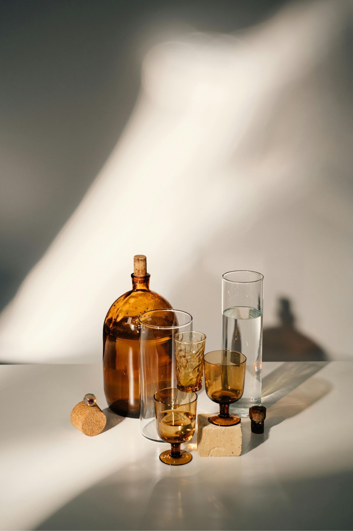 Amber glassware on a white surface, with shadows cast on a white wall.